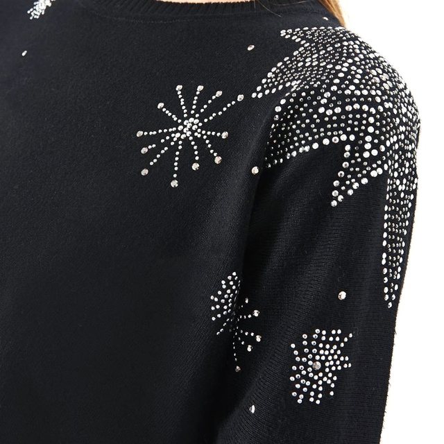 Hombro de un sweater negro con estrellas y destellos de piedras, en densidades distintas
